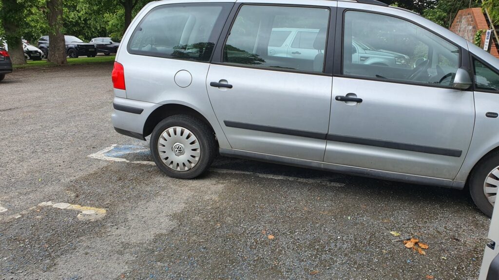 Car parked across lines in disabled parking space