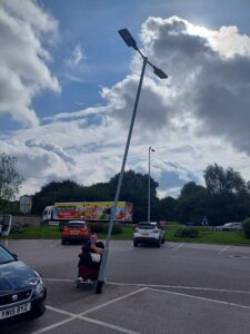 Helen in her powered chair with a lampost with a bigger lean than the leaning tower of pisa