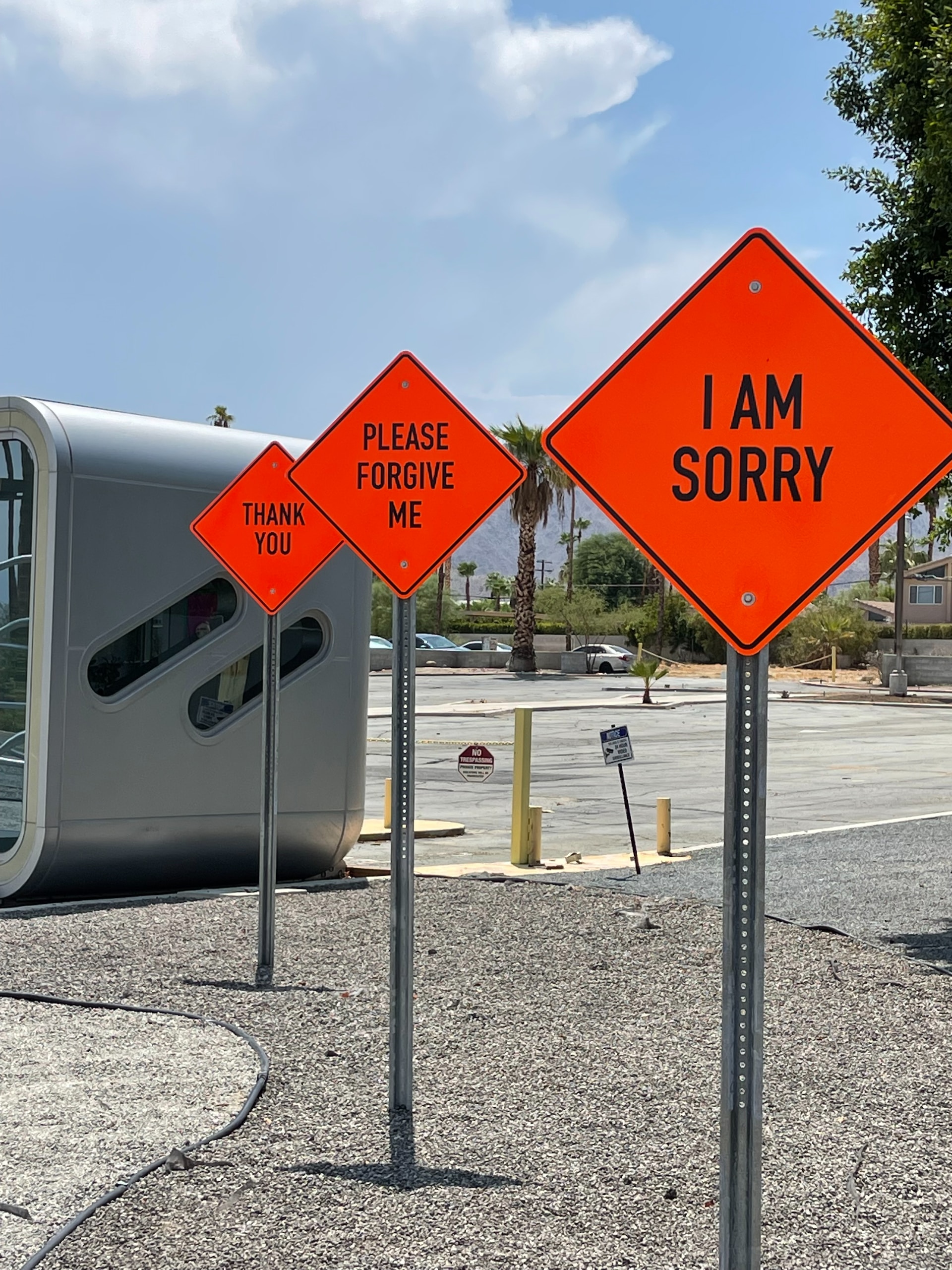 A series of bright orange diamond shaped road signs stating I am sorry