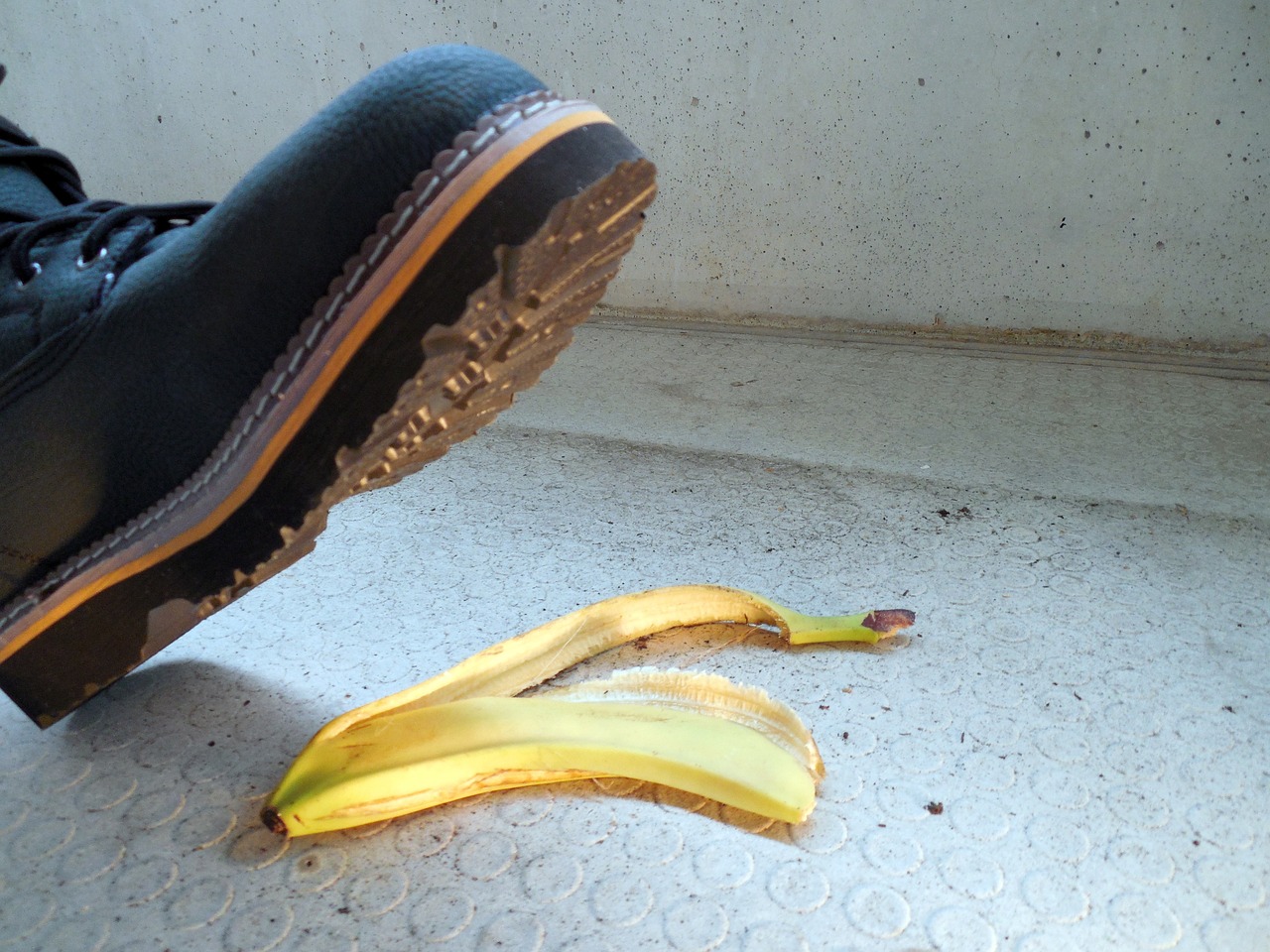 a close up picture of a booted foot about to step on a discarded banana peel