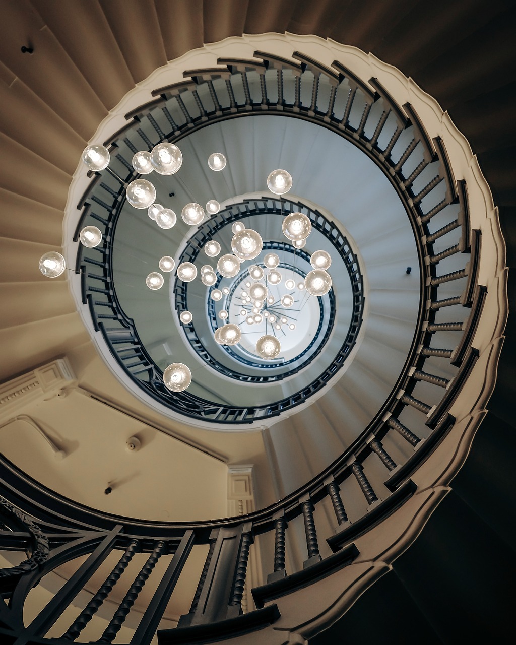 looking up the centre of a spiral staircase with hanging chandilier lights