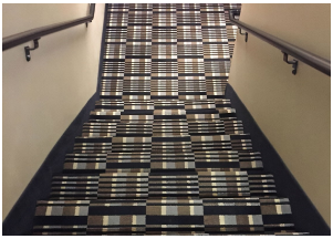 A carpetted staircase with a crazy pattern that disguises the actually stairs